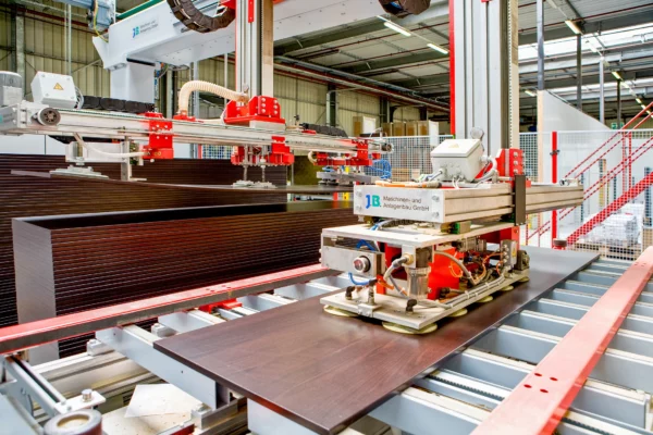 Robot de manutention automatisé déplaçant des panneaux sur une chaîne de production dans l'usine Alsapan.