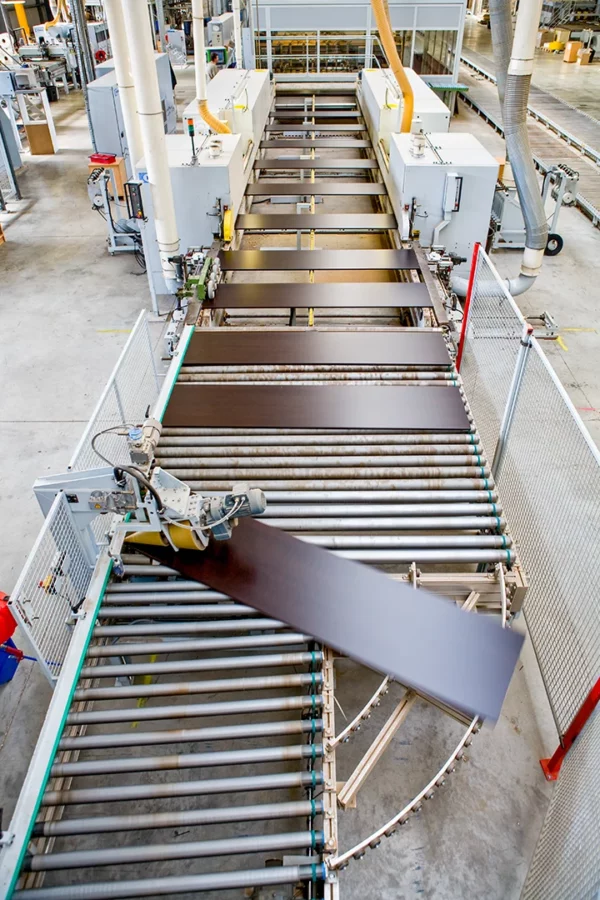 Vue en plongée d'une ligne de production automatisée transportant des panneaux dans l'usine Alsapan.