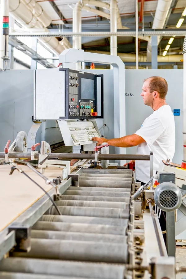Opérateur pilotant un centre d'usinage à commande numérique (CNC) pour la fabrication de panneaux dans l'usine Alsapan.
