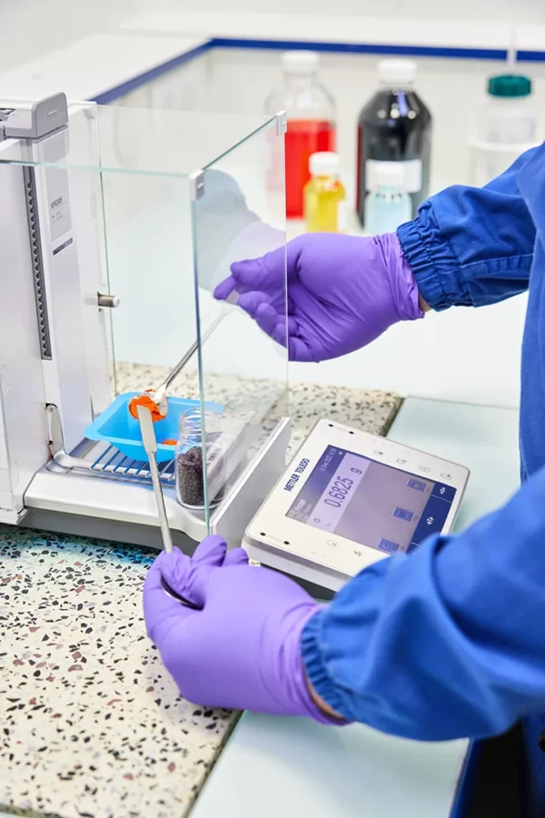 Technicien réalisant une analyse de contrôle qualité sur une balance de précision dans le laboratoire de Cosmeurop à Strasbourg.
