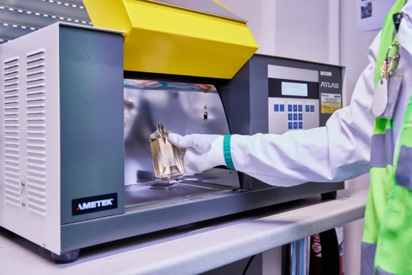 Technicien réalisant le contrôle qualité colorimétrique d'un flacon de parfum à l'aide d'un spectrophotomètre dans l'usine Cosmeurop à Strasbourg.