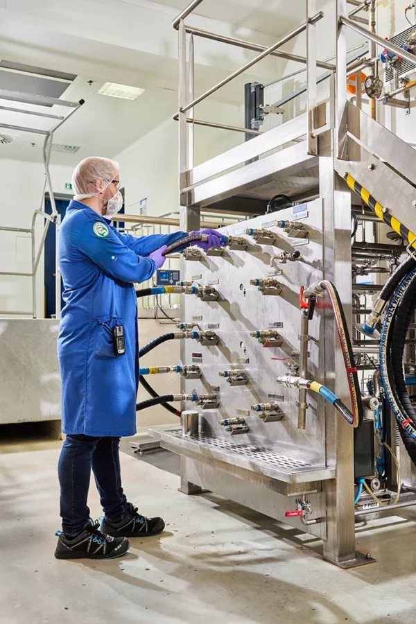 Technicien contrôlant les raccordements d'un équipement de production dans l'usine Cosmeurop à Strasbourg.