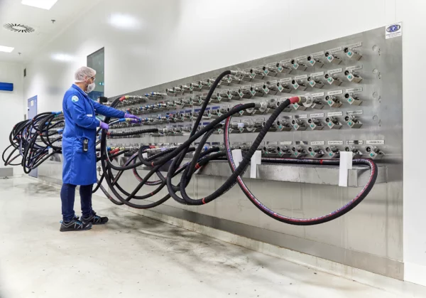 Technicien raccordant les circuits de transfert de matières premières sur un panneau de distribution dans l'unité de production cosmétique de Cosmeurop à Strasbourg.