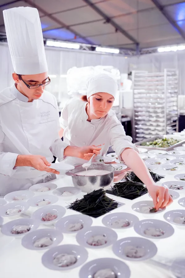 Brigade de cuisine dressant les assiettes lors des préparatifs du gala au Palais des Congrès de Strasbourg