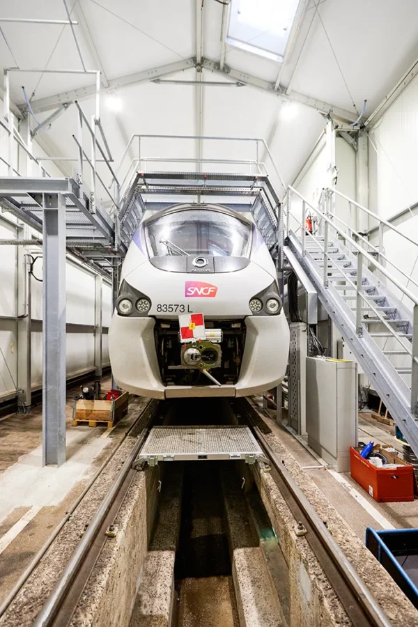 Rame SNCF immobilisée dans un atelier de maintenance ferroviaire à Strasbourg avec passerelles techniques d'inspection.