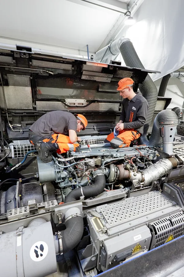 Techniciens réalisant une opération de maintenance sur le moteur d'une rame SNCF dans un atelier ferroviaire à Strasbourg.