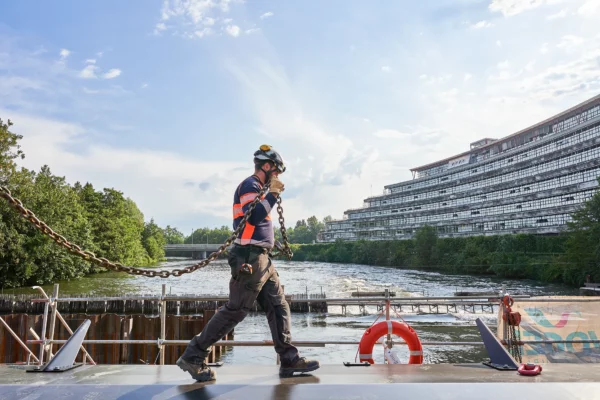 Ouvrier transportant une chaîne pour la manutention d'un clapet sur un chantier VNF à Strasbourg dans le cadre d'un reportage photo de suivi de chantier.