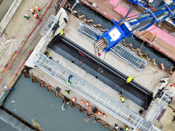 Vue aérienne verticale montrant la pose d'un clapet hydraulique au moyen d'une grue sur un chantier VNF à Strasbourg dans le cadre d'un suivi de chantier.