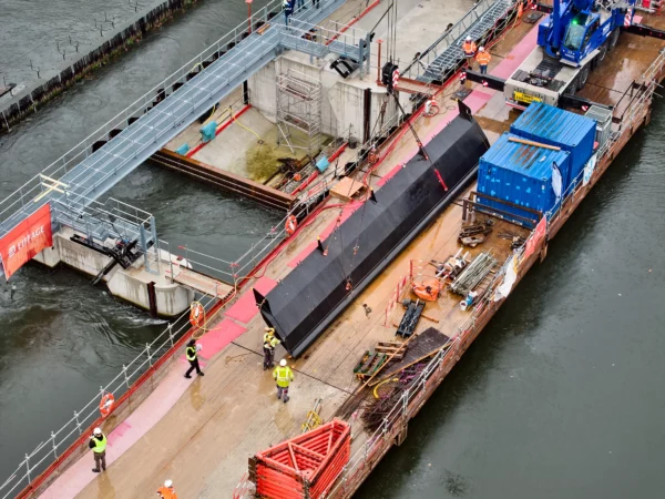 Vue aérienne du transport d'un clapet hydraulique sur une barge lors d'un suivi de chantier VNF à Strasbourg.