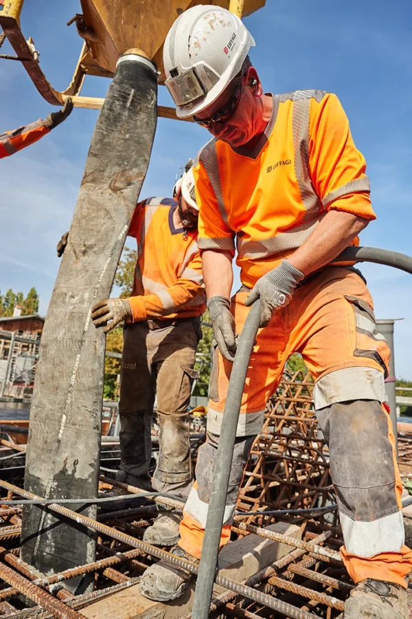 Ouvrier utilisant une aiguille vibrante pour compacter le béton lors d'un coulage dans le cadre d'un suivi de chantier VNF à Strasbourg.